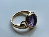 a close up of a gold ring with a purple stone