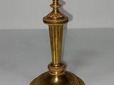 une bougie dorée posée sur une table blanche