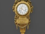 une horloge dorée accrochée au mur sur un fond noir