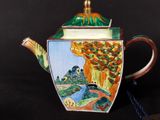 a teapot with a painting on it sitting on a table