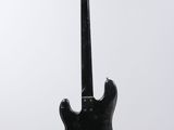 a black electric guitar on a stand against a white background