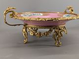 a gold and pink bowl on a stand on a gray surface
