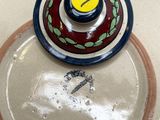une assiette blanche avec un couvercle rouge et jaune