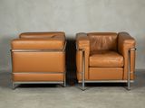two brown leather chairs sitting next to each other in a room