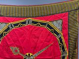 a red and black blanket with a gold and black design on it