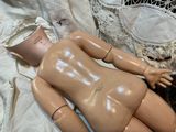 a naked doll laying on a bed with a lace headband
