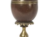 une image représentant une urne aux couleurs marron et doré posée sur un socle en bois