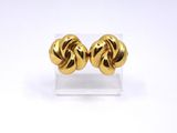 a pair of gold plated earrings on a clear stand