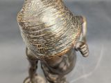 bronze figurine of a boy with a hat on his head