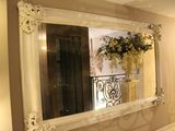 un grand miroir accroché au mur au-dessus d'un lavabo
