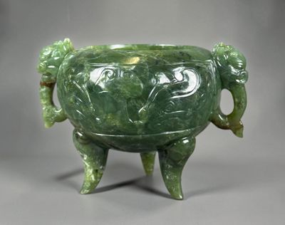 un vase vert orné de deux éléphants, posé sur un socle