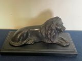 statue d'un lion posée sur un socle noir, sur un fond bleu