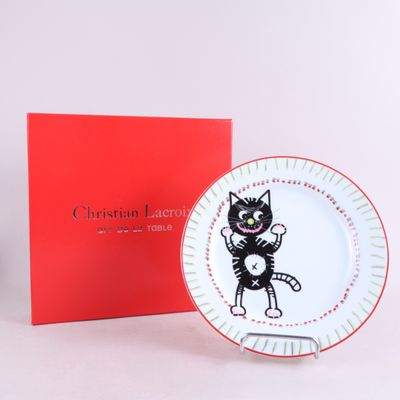 un chat noir et blanc assis sur une assiette à côté d'une boîte rouge