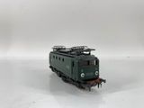 a green train on the tracks on a white surface