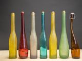 Plusieurs bouteilles en verre de différentes couleurs sont alignées sur une table