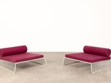 une paire de chaises longues avec des coussins rouges dans une pièce blanche