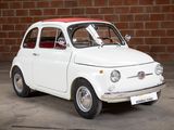 a small white car that is parked in front of a brick wall
