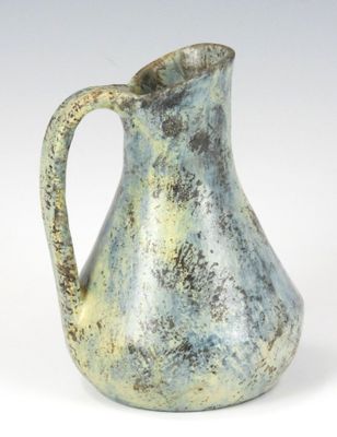 un vase bleu et vert muni d'une anse, posé sur une surface blanche