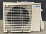 an air conditioner sitting on top of a cement floor next to a black wall