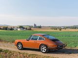 an orange car parked on a dirt road next to a field