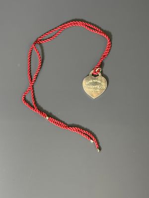a close up of a red rope with a heart shaped tag on it