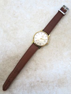 une photo d'une montre posée sur une surface blanche