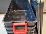 a stack of black and red plastic containers on the floor