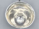 a close up of a silver bowl on a white surface