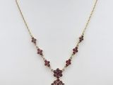 un collier avec une pierre rouge et une chaîne en or sur un mannequin