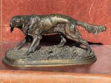 statue en bronze représentant un chien sur un socle, avec un fond rouge