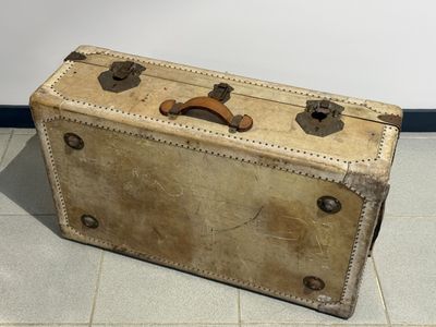 une vieille valise posée par terre dans une pièce