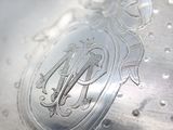 a close up of a silver vase with a monogram on it