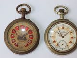 deux vieilles montres de poche posées côte à côte sur une surface blanche
