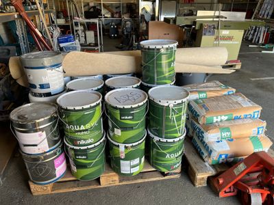 de nombreux seaux de peinture posés sur une palette dans un garage