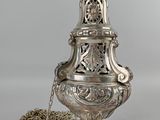 un vase en argent richement décoré, d'une chaîne suspendue à son col