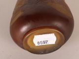 a brown vase with a label on it on a white surface