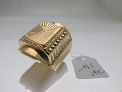 une bague en or posée sur une surface blanche, avec une étiquette de prix