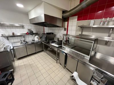 une grande cuisine équipée d'appareils électroménagers en inox et aux murs rouges