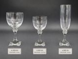 three clear wine glasses with labels on them sitting on a table