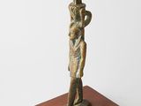 une statue égyptienne représentant un homme tenant une épée, posée sur un socle en bois