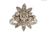 une image représentant une bague ornée d'une fleur en diamant sur fond blanc