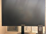 a computer monitor sitting on a window sill next to a cell phone