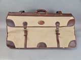 an image of a tan and brown suitcase sitting on top of a table