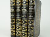 un lot de quatre livres noirs et dorés empilés les uns sur les autres