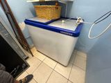 une machine à laver bleue et blanche dans une petite pièce