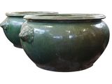 deux vases verts posés l'un à côté de l'autre sur une surface blanche
