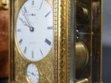 a gold clock sitting on a table next to a book