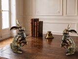 two statues of rabbits sitting on a table in a room