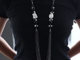 a woman wearing a black shirt and a long necklace