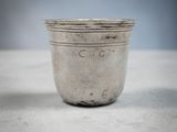 an old silver cup sitting on top of a white table